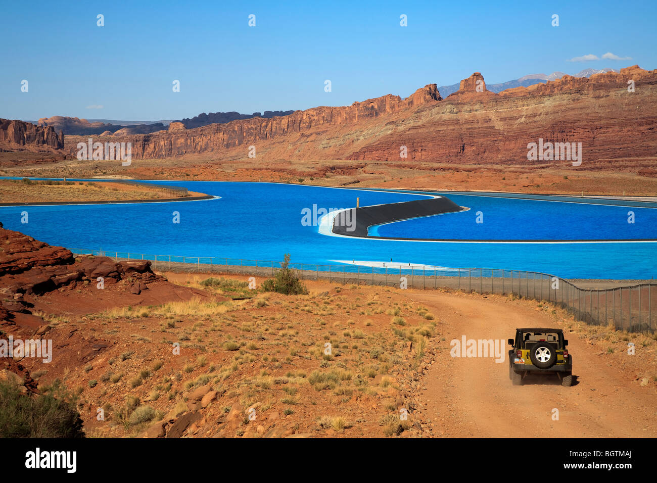 Scene overlooking the bight blue Cane Creek potash mine water evaporation ponds near Moab, Utah, USA and 4x4 truck in foreground Stock Photo