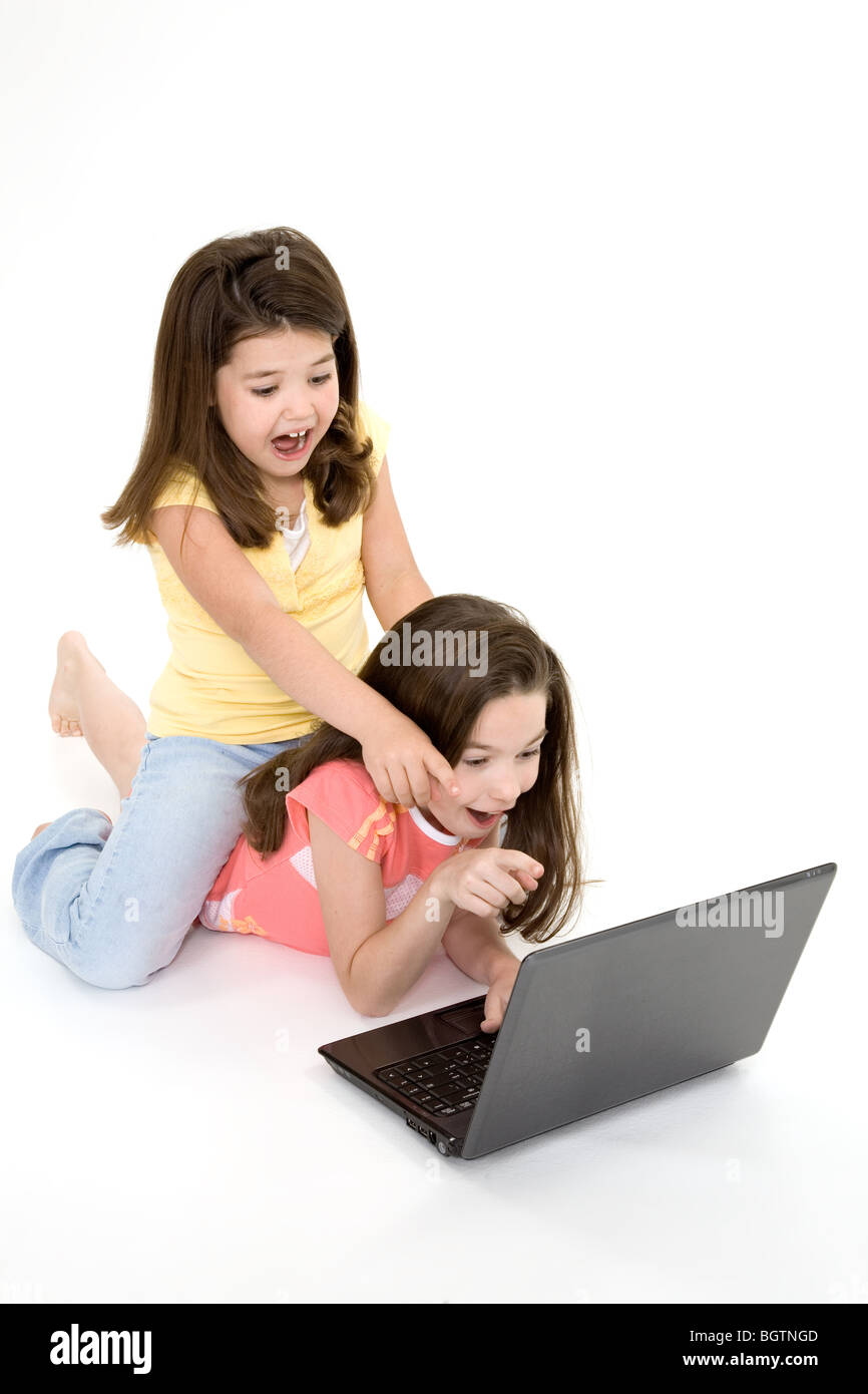 Sisters playing on a laptop computer on a white background Stock Photo ...