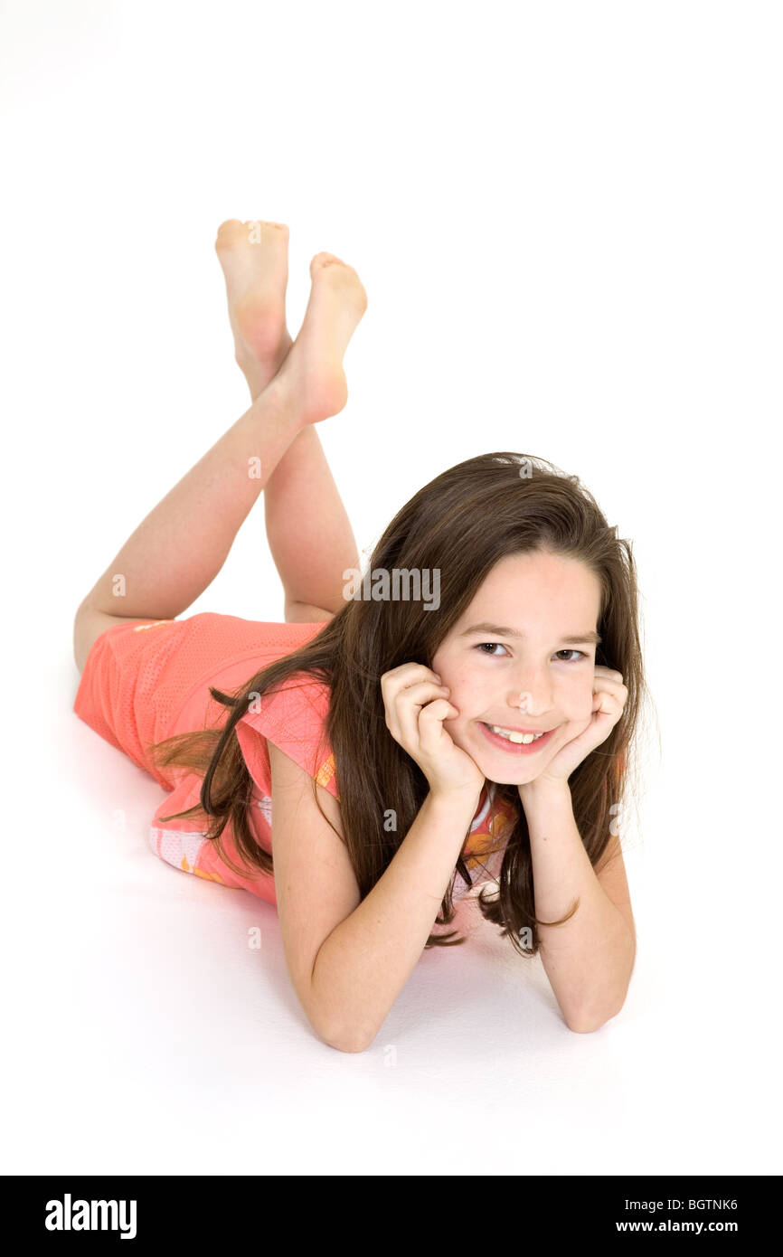Eight year old female child laying on white background smiling wearing casual clothes Stock Photo