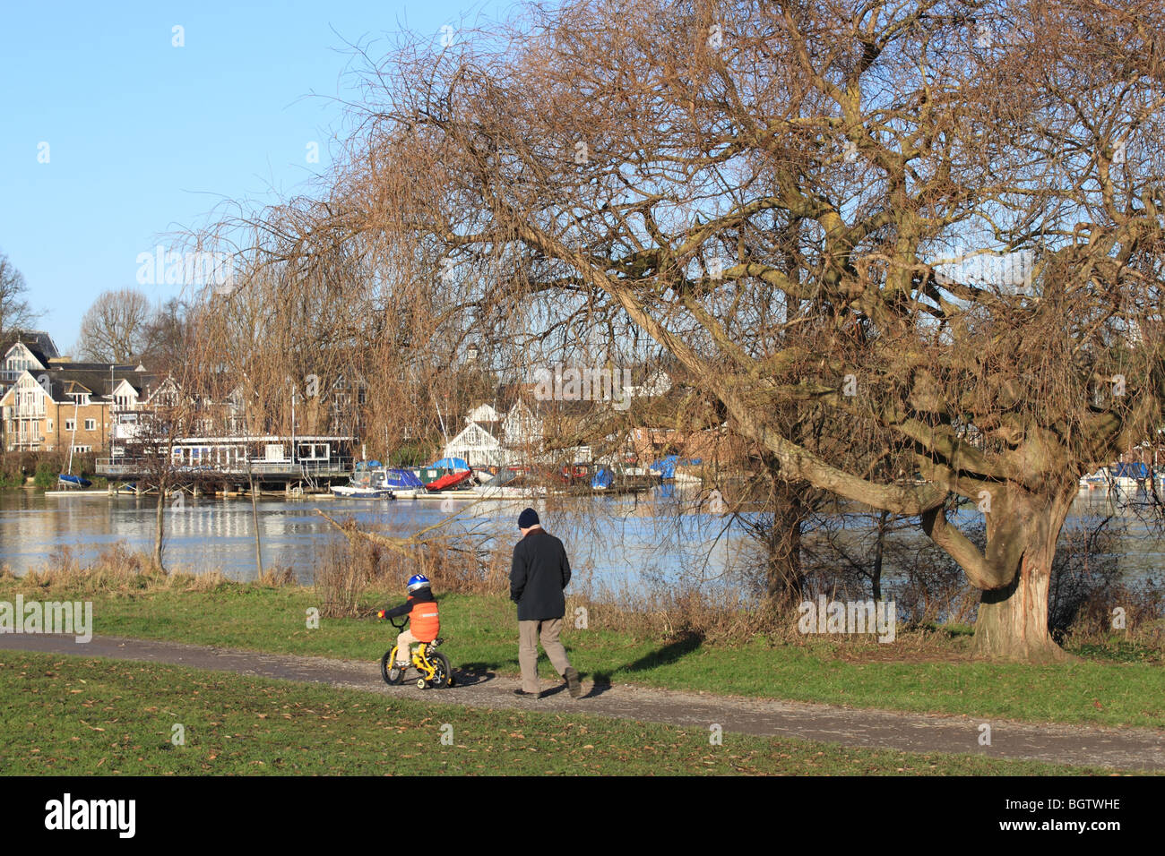 Child on bicycle and man at the riverside open space at Sadler's Ride, Hurst Park, East Molesey, Surrey, England, Great Britain, UK, Europe Stock Photo