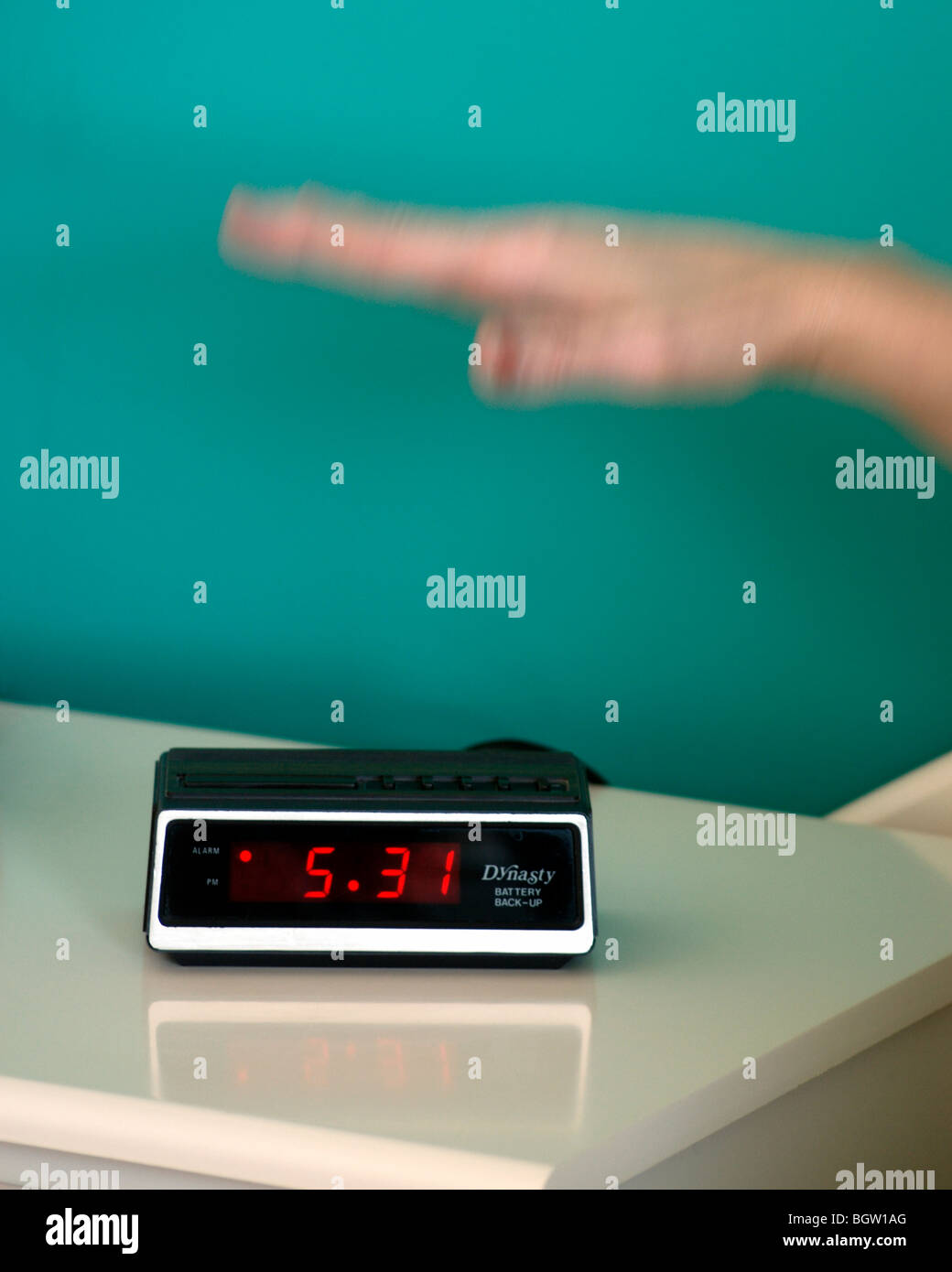 Hand reaching for alarm clock Stock Photo