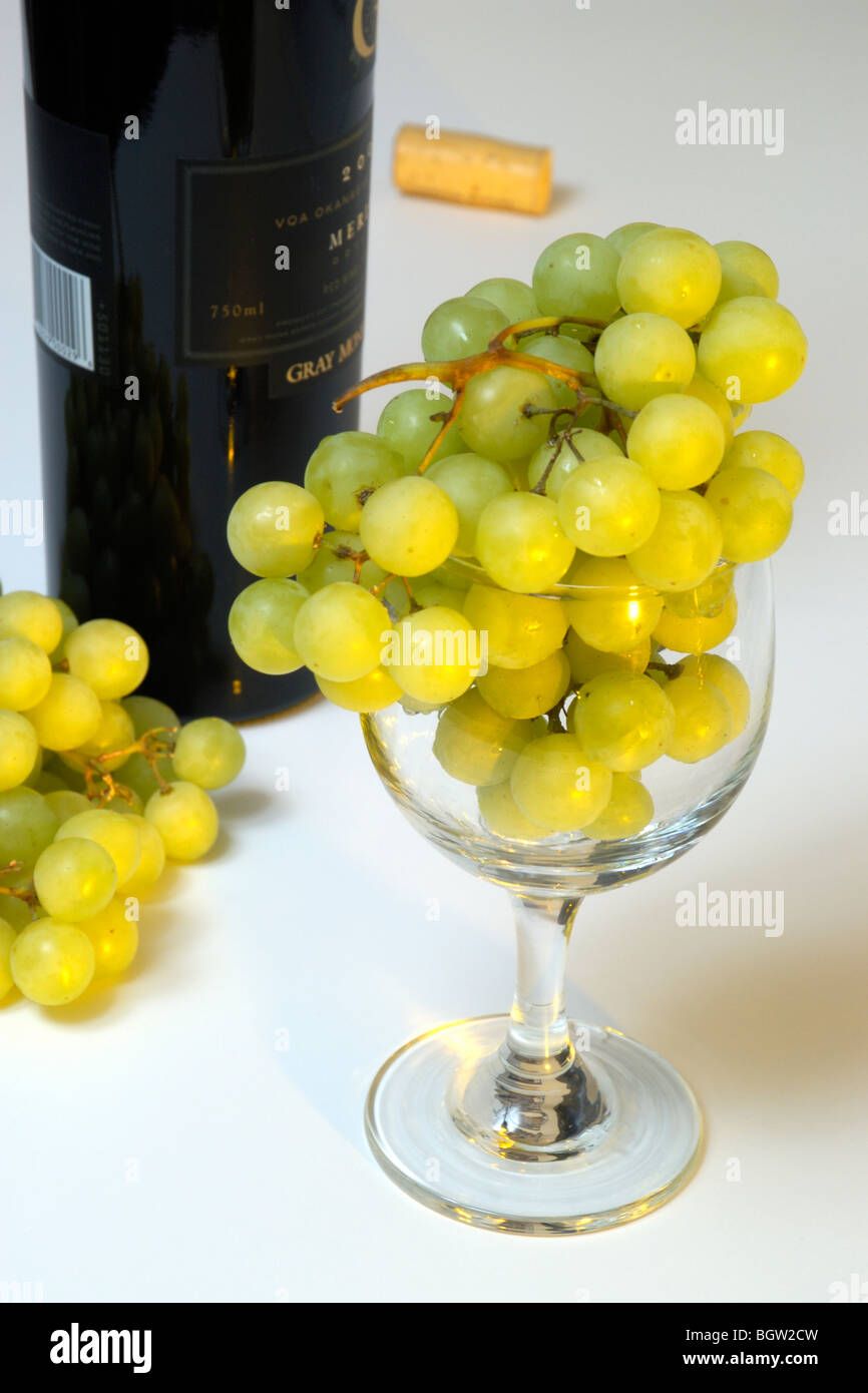 Grapes in glass beside wine bottle Stock Photo