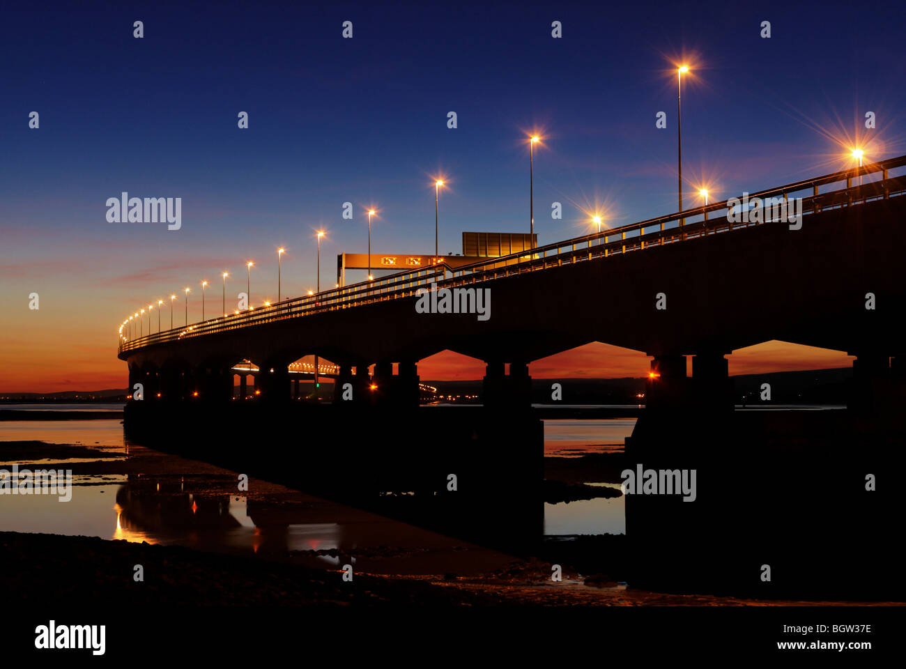 Low tide view of the second Severn crossing at dusk with the lights of the M4 motorway lit up Stock Photo