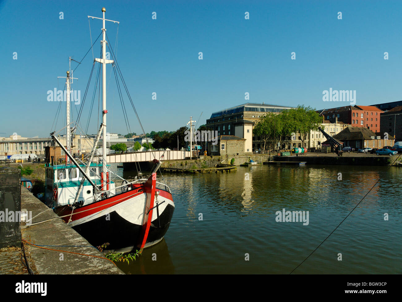 A view of Bristol Docks from Merchants quay with a colourful freshly painted boat tied up and old warehouses in the distance Stock Photo