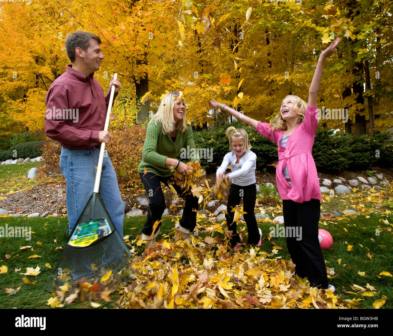 Family raking leaves, daughter throwing leaves Stock Photo Alamy