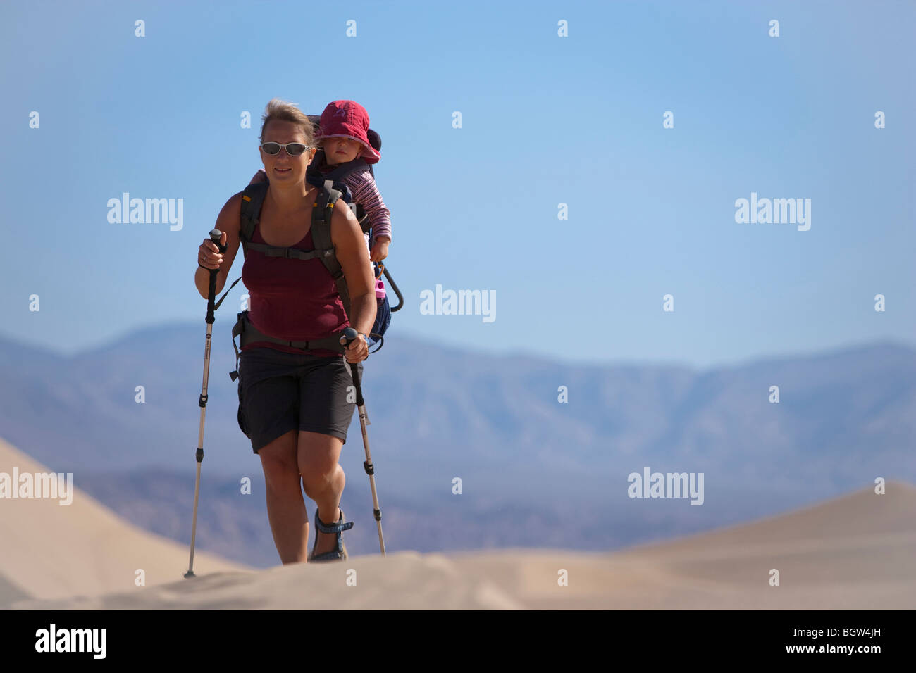 Female hiker carrying child piggy-back in the desert, Death Valley National Park, California, USA Stock Photo