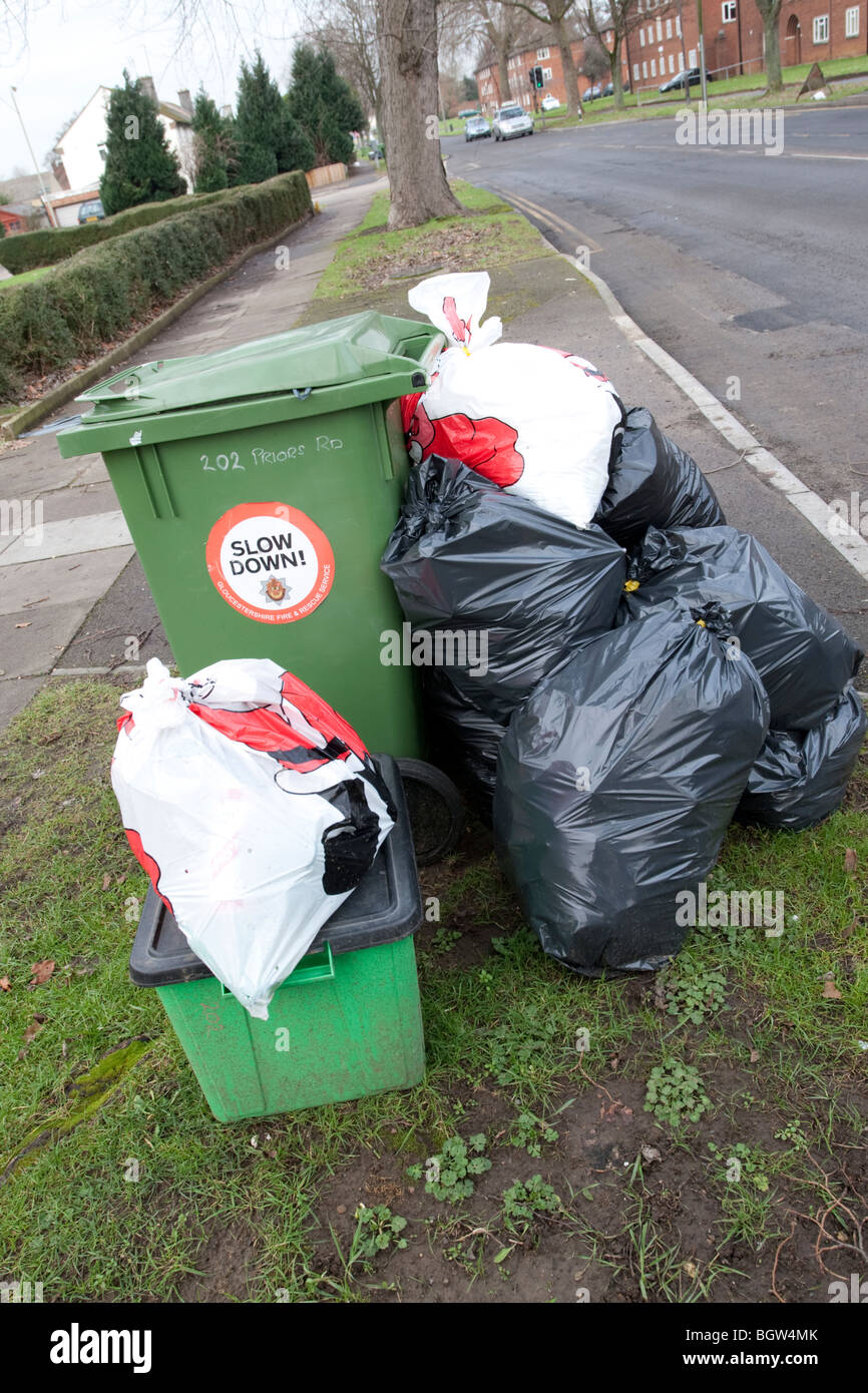 Green wheelie bin overflowing with domestic rubbish awaiting collection ...