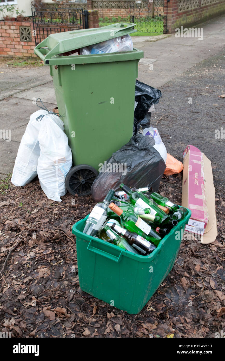 Green wheelie bin overflowing with domestic rubbish awaiting collection Cheltenham UK Stock Photo