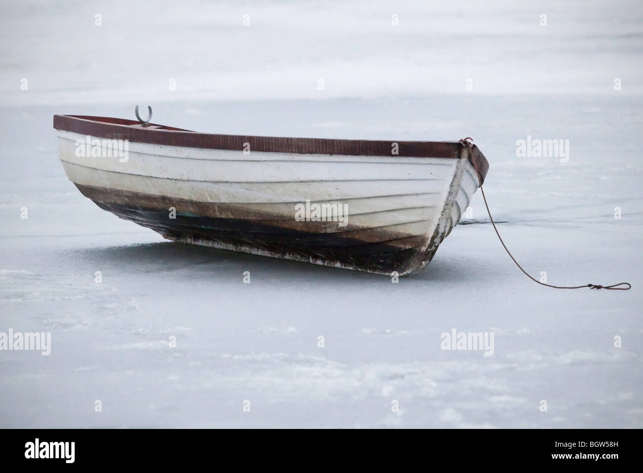 Small boat on an ice covered pond in winter Stock Photo