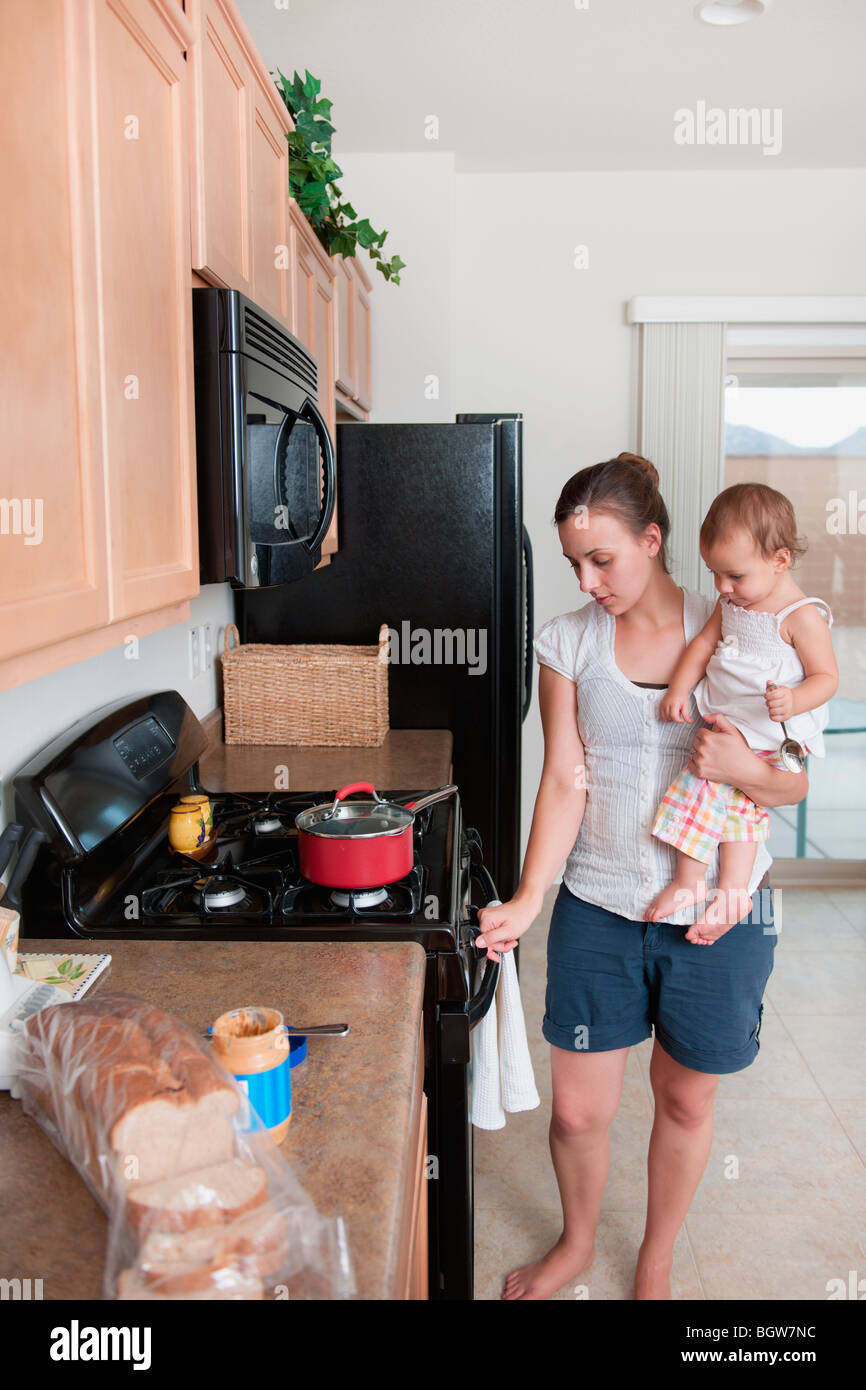 A mother cooking and holding a baby Stock Photo Alamy