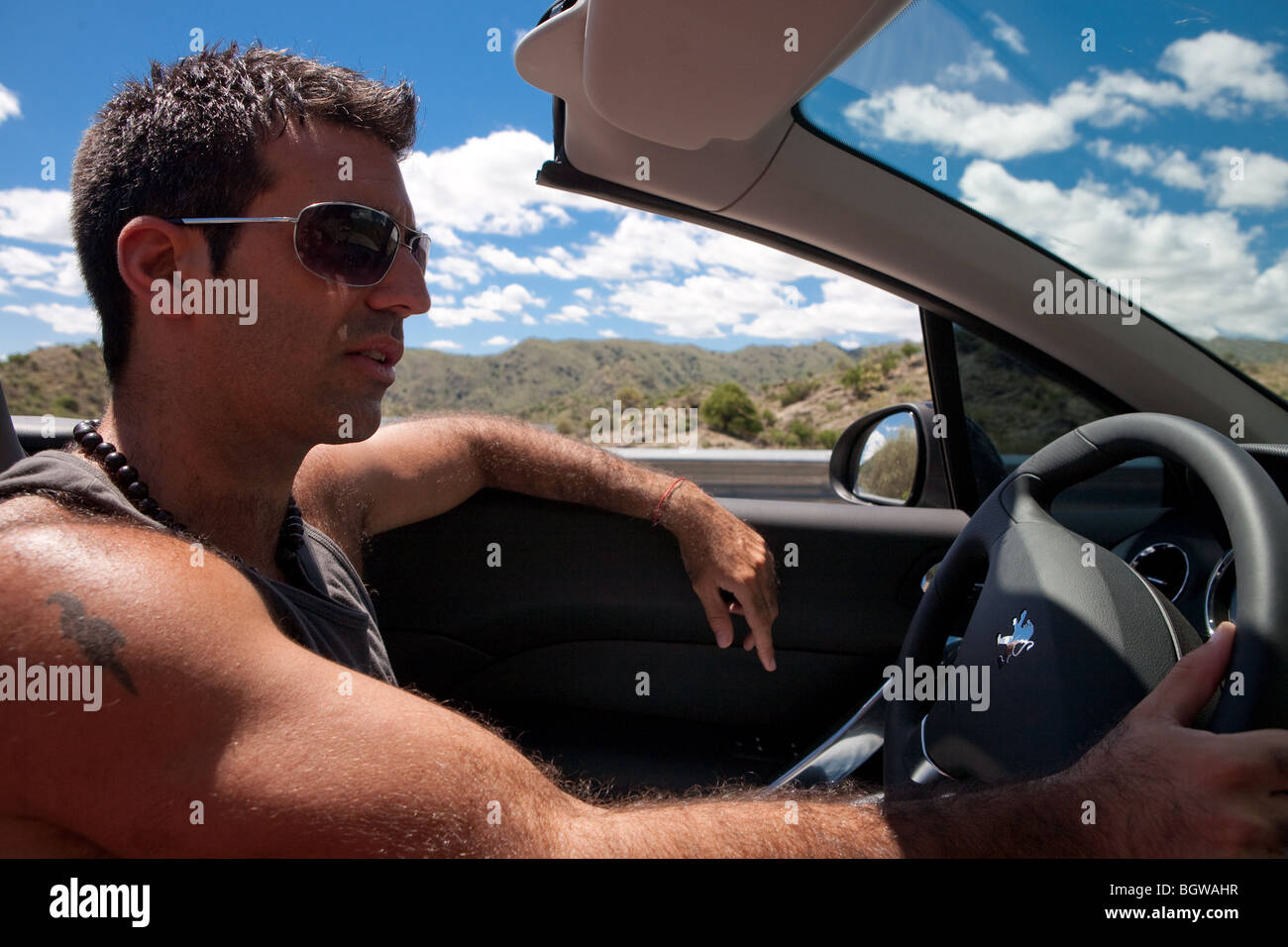 Cool guy driving a convertible car through a desert Stock Photo