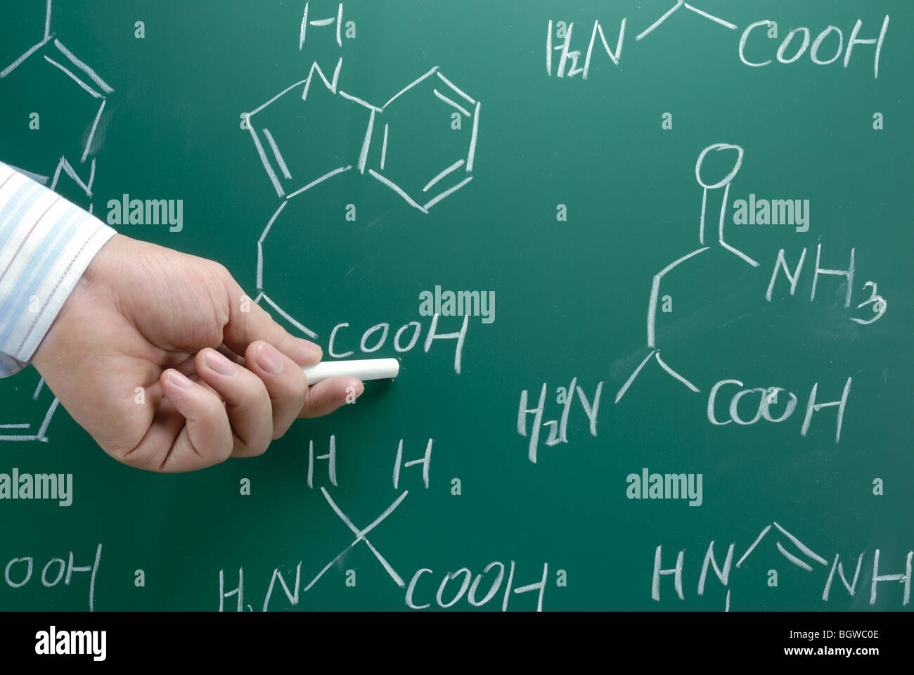 Hand with chalk showing chemical formula on the Chalkboard Stock Photo