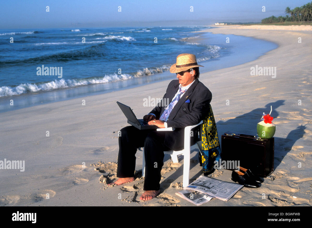 Business traveller seated on the beach and using a laptop in Salalah, Dhofar Oman Stock Photo