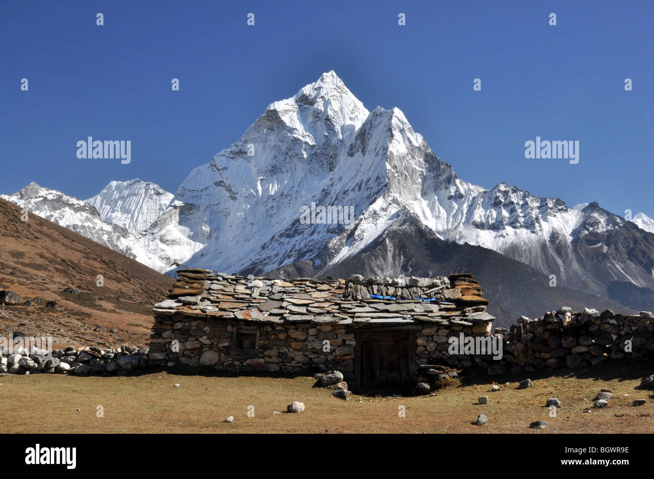 Himalayan mountain home in the shadow of a striking snow capped peak at moonrise Stock Photo