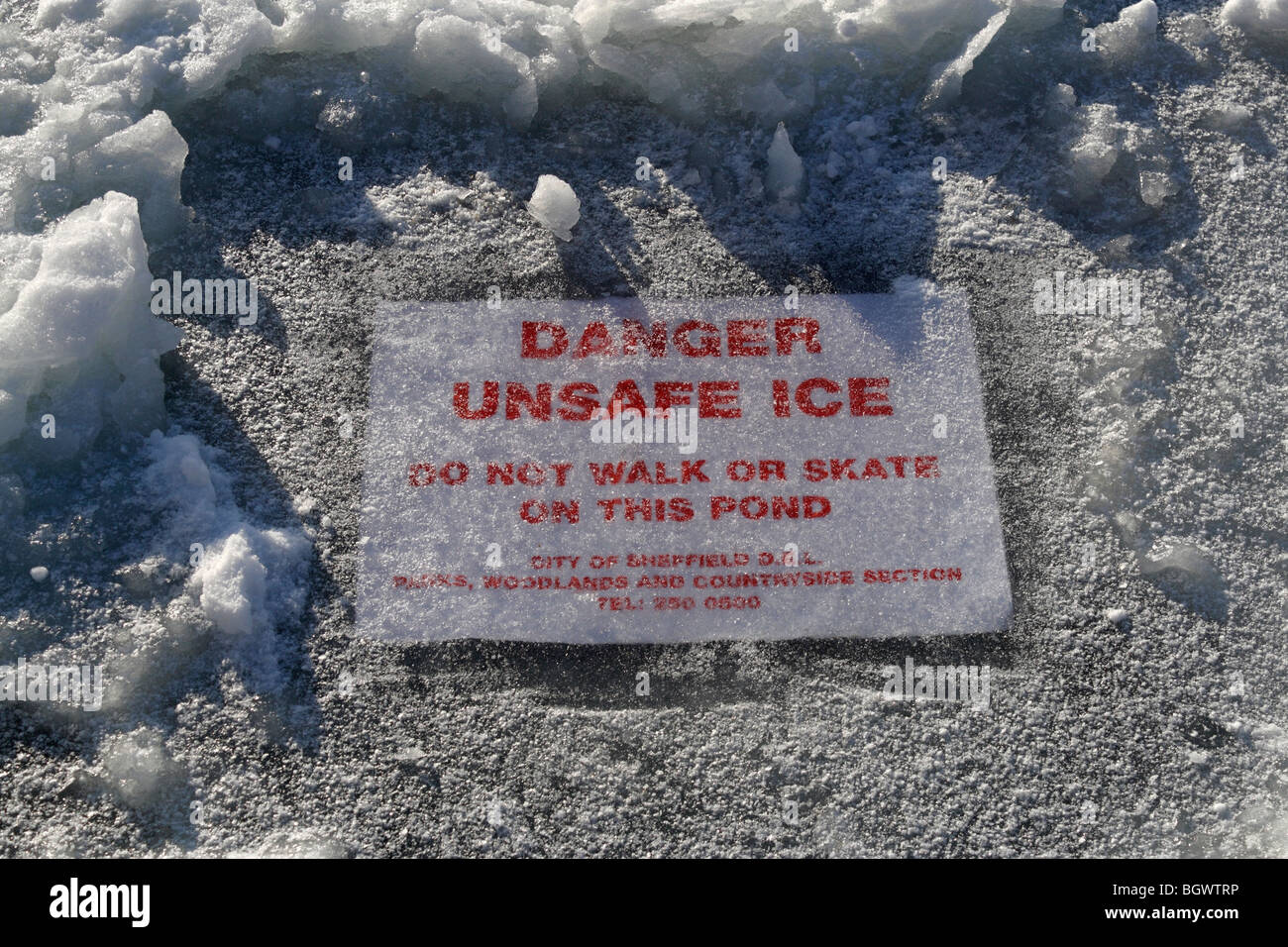 Danger Unsafe Ice sign buried under the surface of the boating lake in Millhouses Park Sheffield England Stock Photo