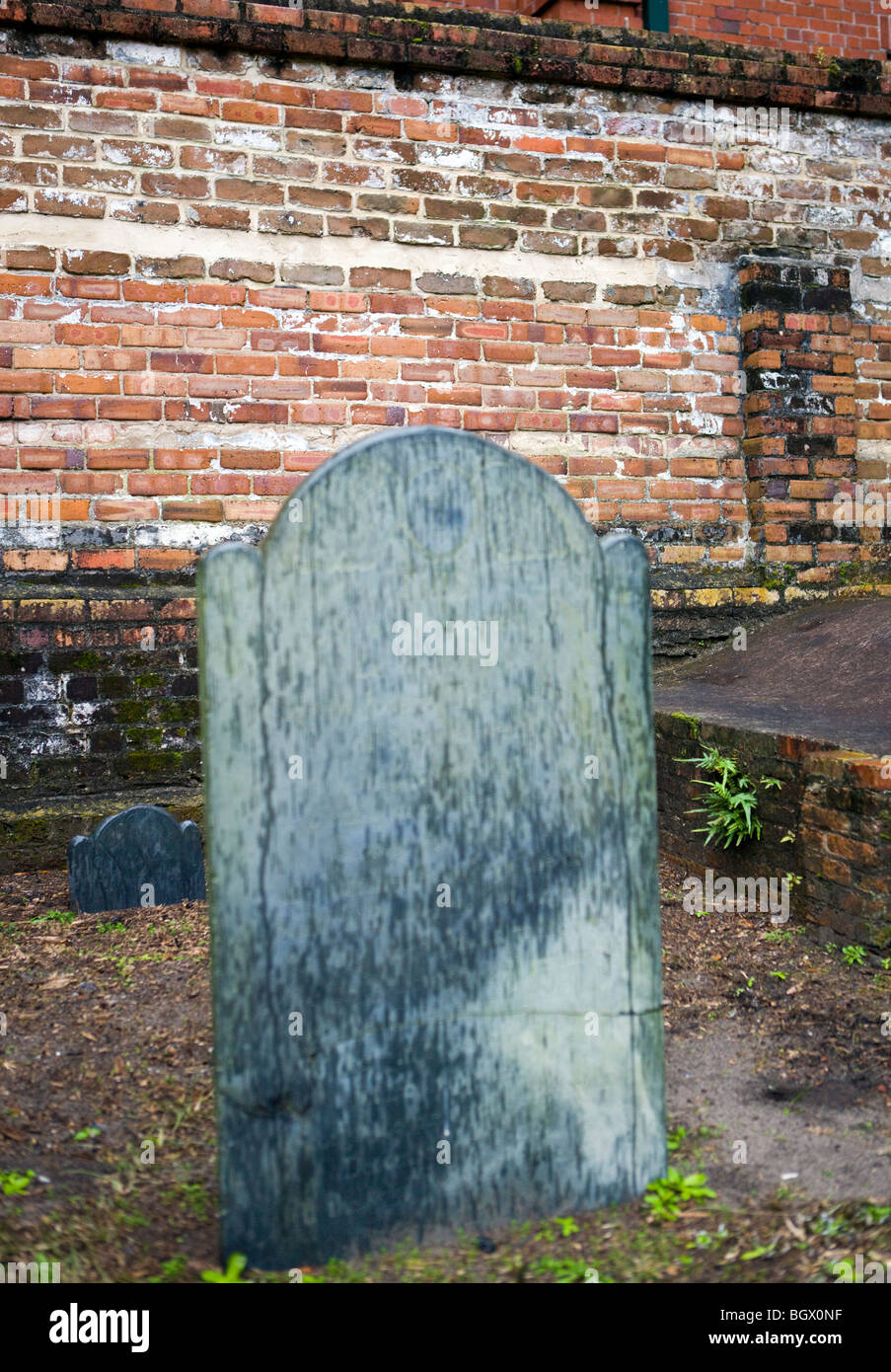Unmarked gravestone in front of brick wall to Centenial Park, commissioned by George Washington, Savannah, Georgia Stock Photo
