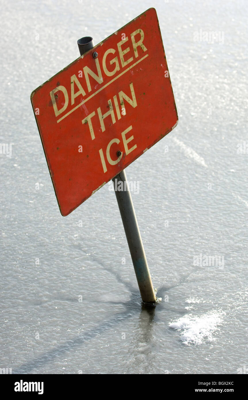 Warning sign informing not to walk onto the lake due to thin ice. Stock Photo