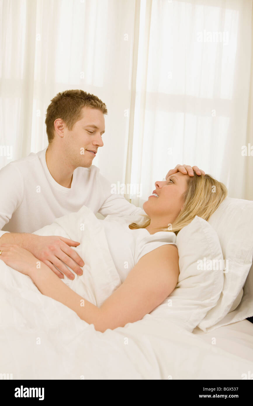 Loving husband caring for sick wife in bed Stock Photo