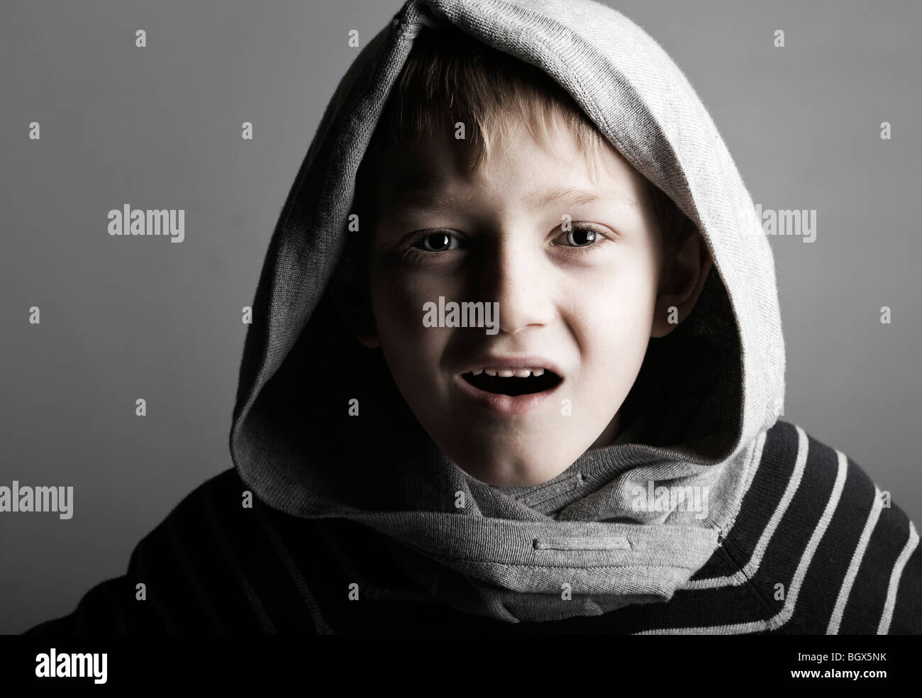 a young blonde boy in a hood with a lot of attitude Stock Photo