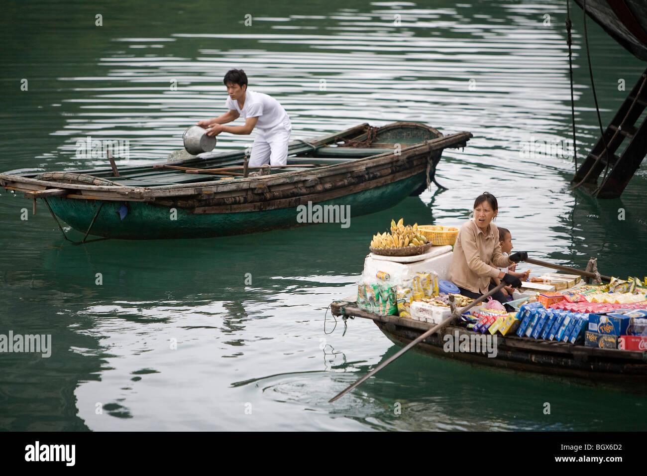 Woman with supplies in boat beside a man bailing his boat out Stock Photo