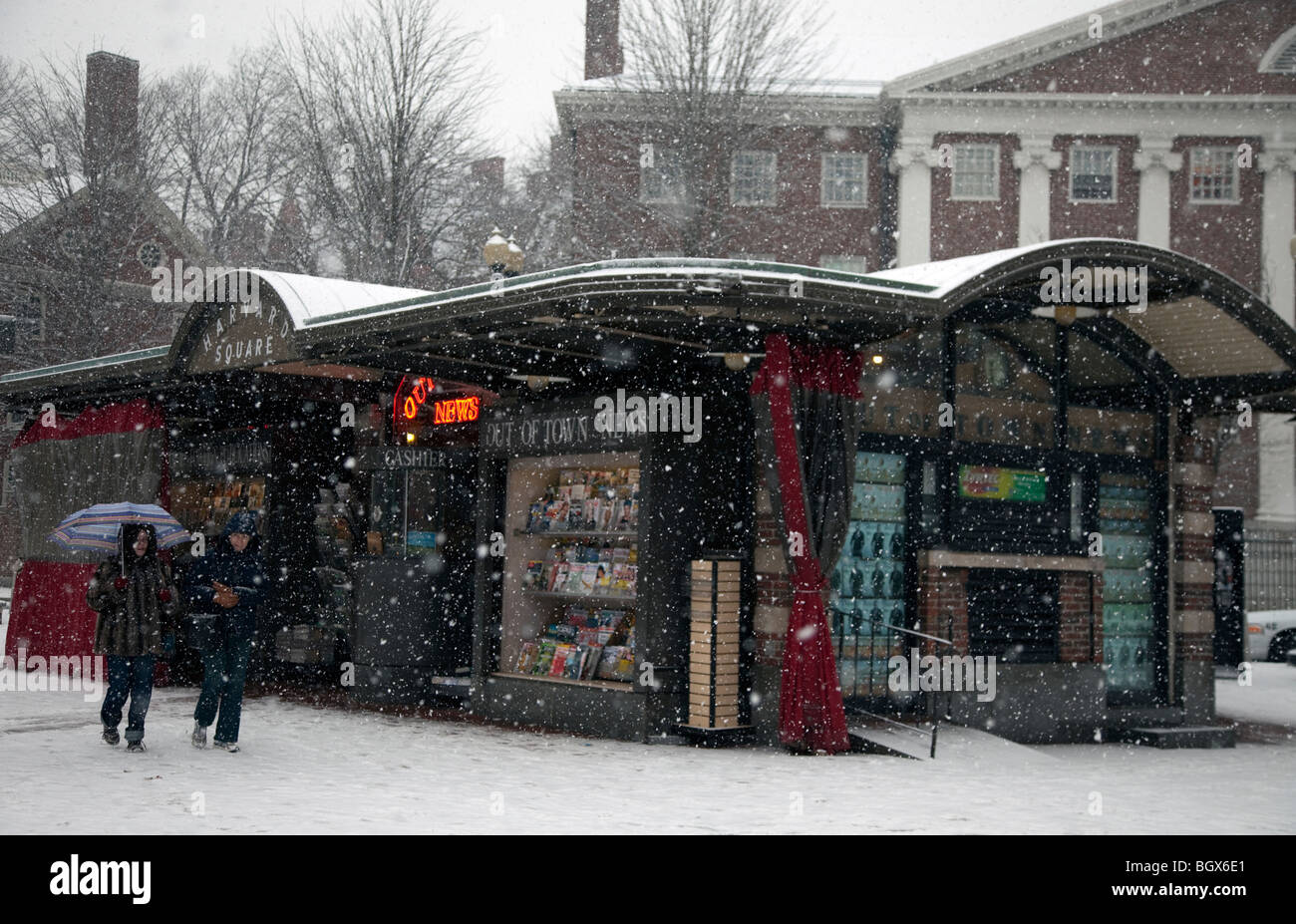 People walking past a newsstand during a snowstorm Stock Photo