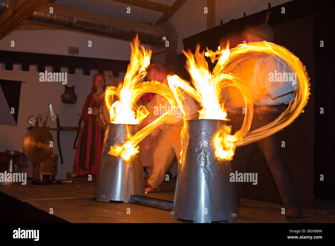 Entertainers using drumsticks lit by fire to beat the drums and entertain guests during a medieval feast at Schloss Auerbach (Au Stock Photo