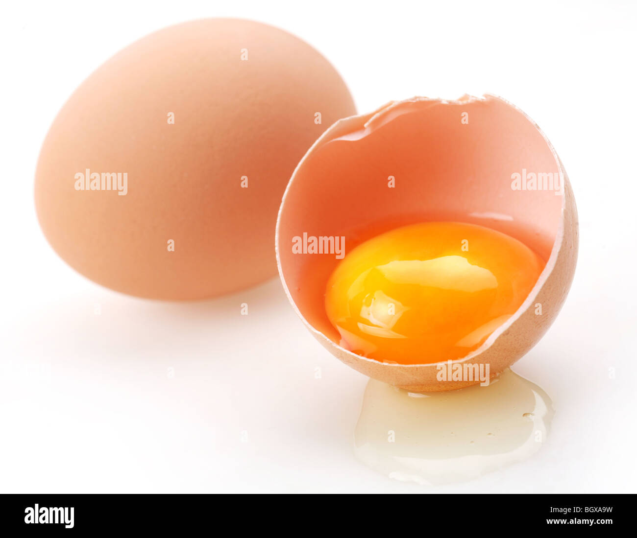 With brown eggs on a white background. One egg is broken. Stock Photo