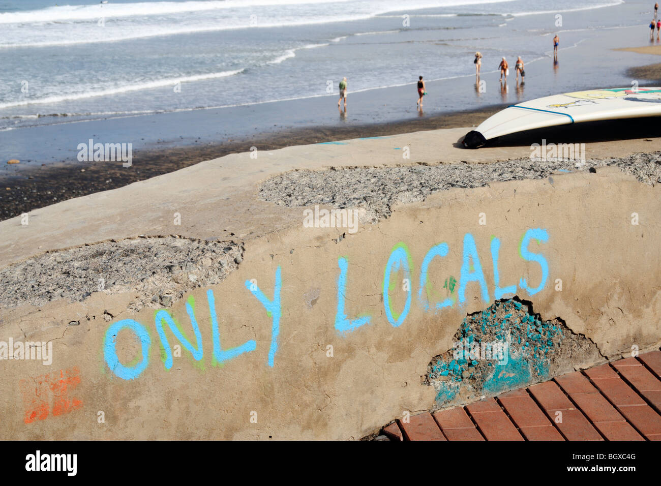 'Only Locals' painted on wall at surf break. Could be used as Brexit/isolation/ immingration... concept image Stock Photo