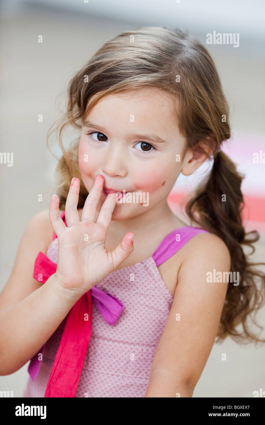 young girl licking her fingers Stock Photo