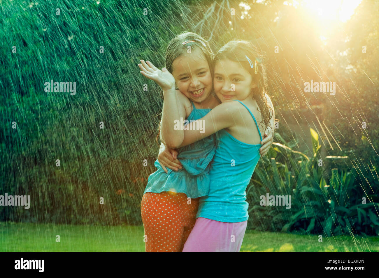Girls standing in rain hugging Stock Photo - Alamy