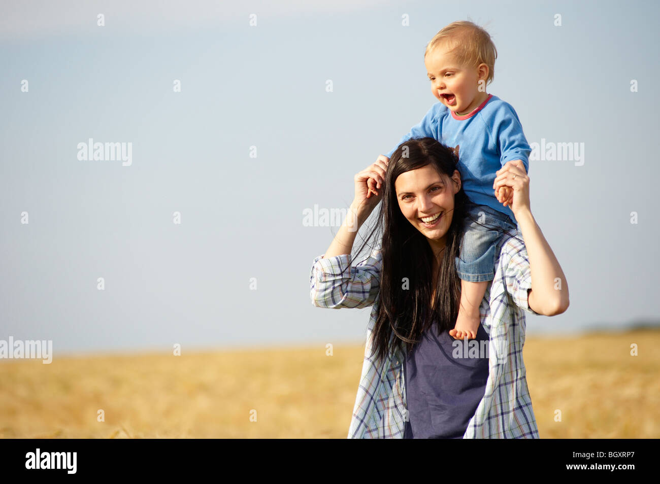 Woman with baby on shoulders, outdoors Stock Photo