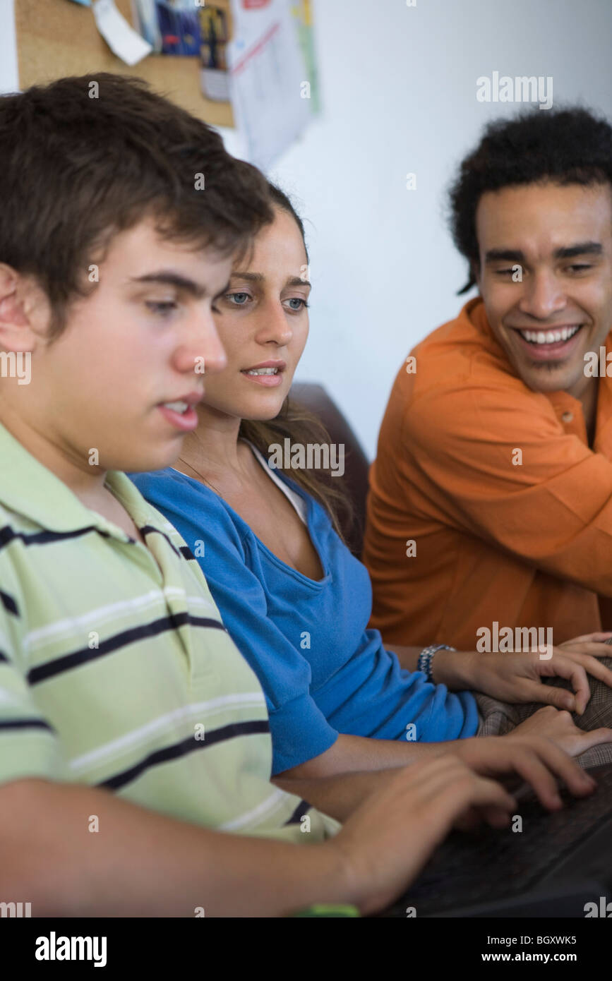 Male college student using laptop computer, classmates sitting ...