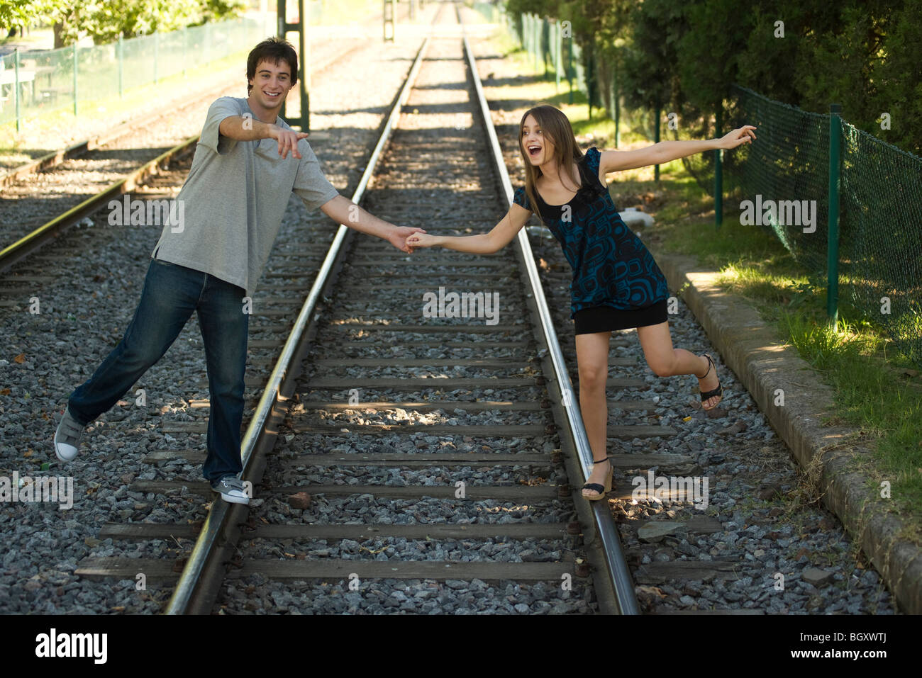 Young couple walking on rail track, holding hands Stock Photo