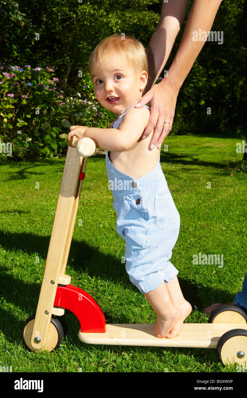 Baby boy on scooter in the garden Stock Photo