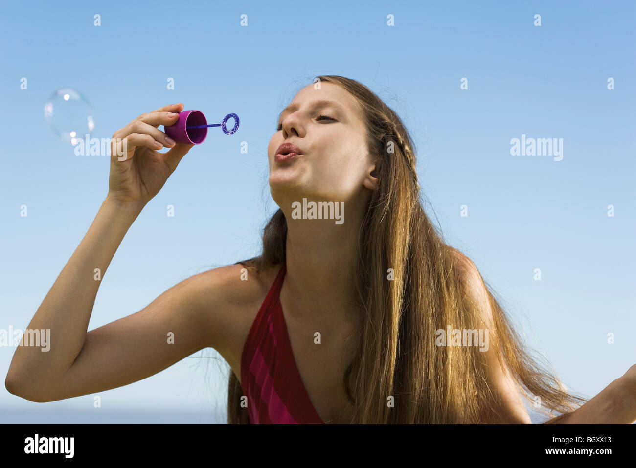 Young woman with bubble wand blowing bubbles Stock Photo