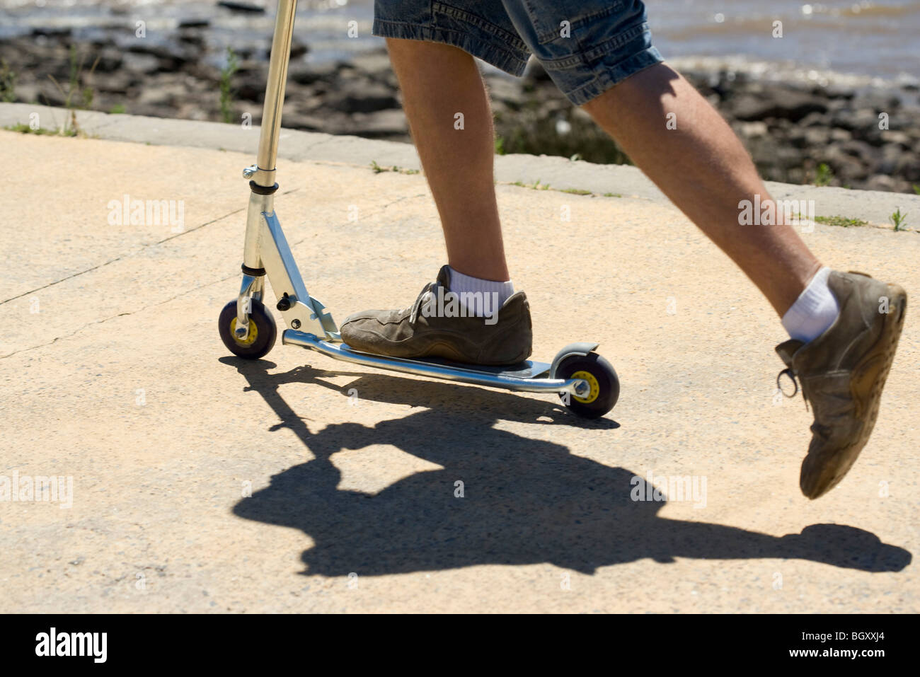 Riding push scooter at seaside Stock Photo