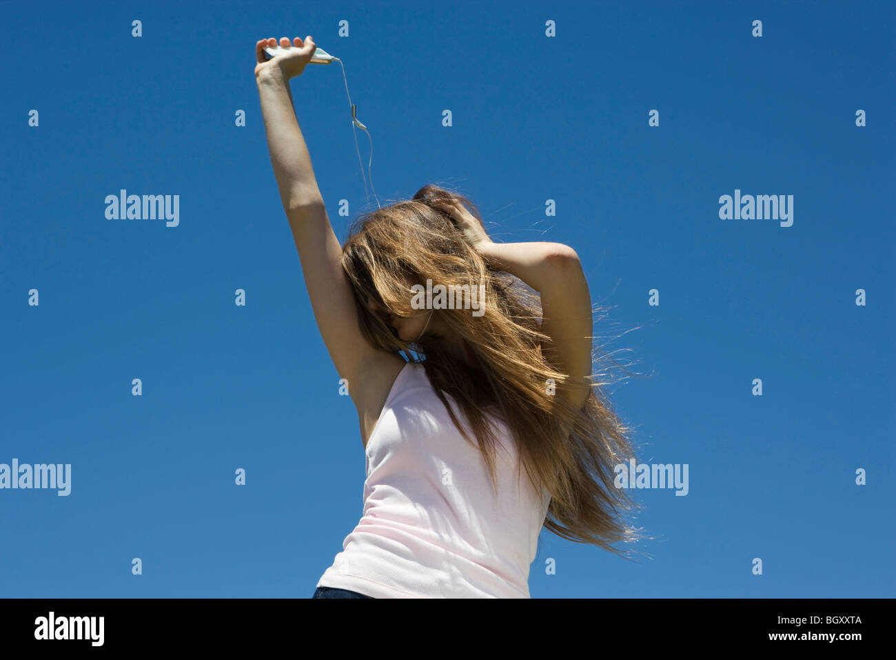 Young woman listening to MP3 player, dancing outdoors Stock Photo