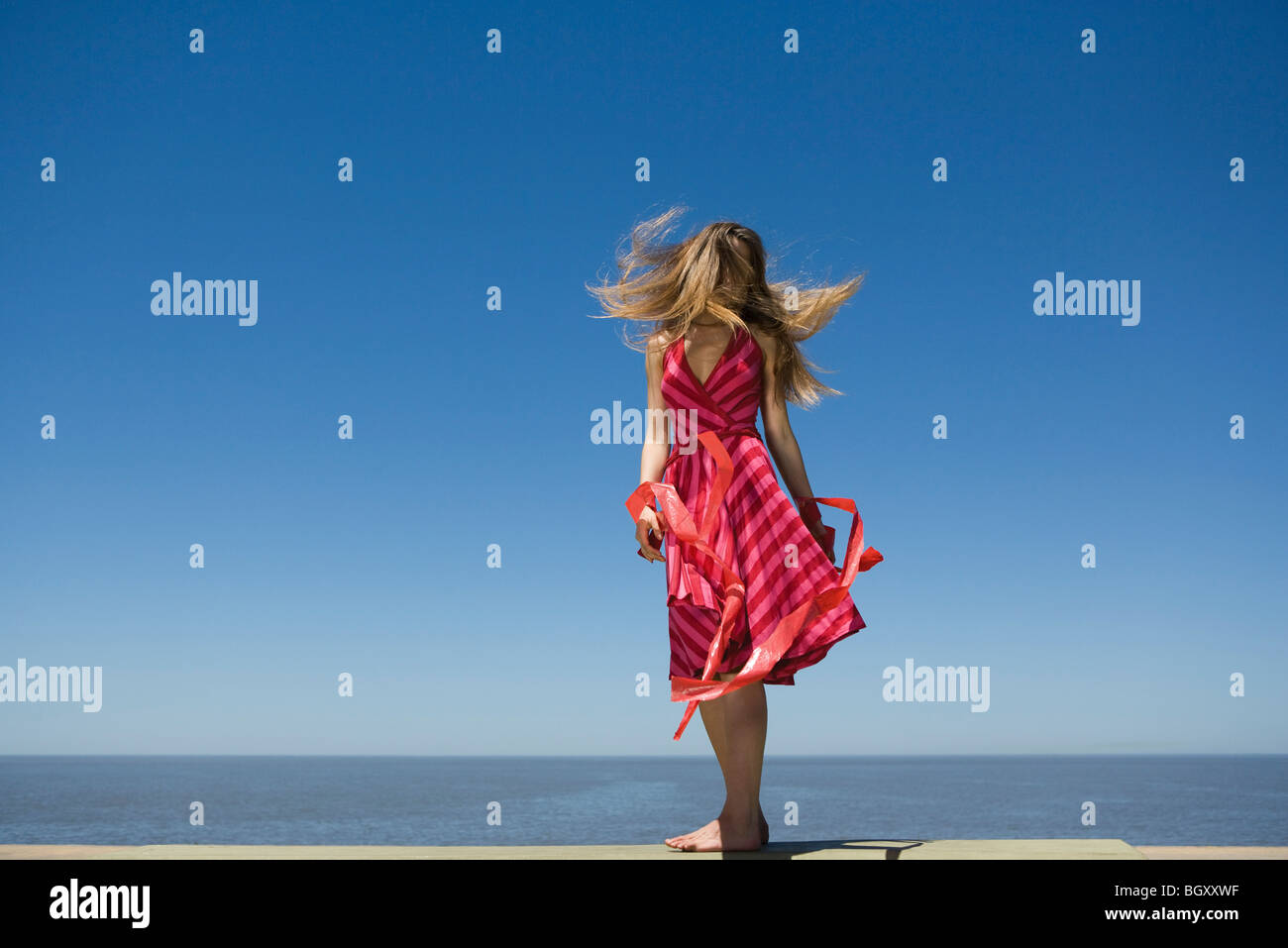 Young woman at beach enjoying sunshine, tossing hair Stock Photo