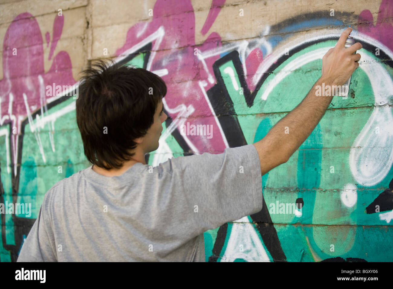 Young man spray painting graffiti mural Stock Photo