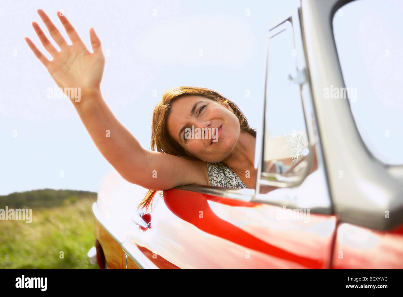 mid-aged woman's hand out of car window Stock Photo