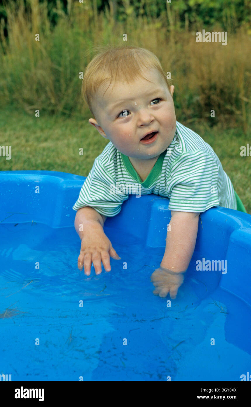 baby boy testing the temperature of the water in his paddling pool