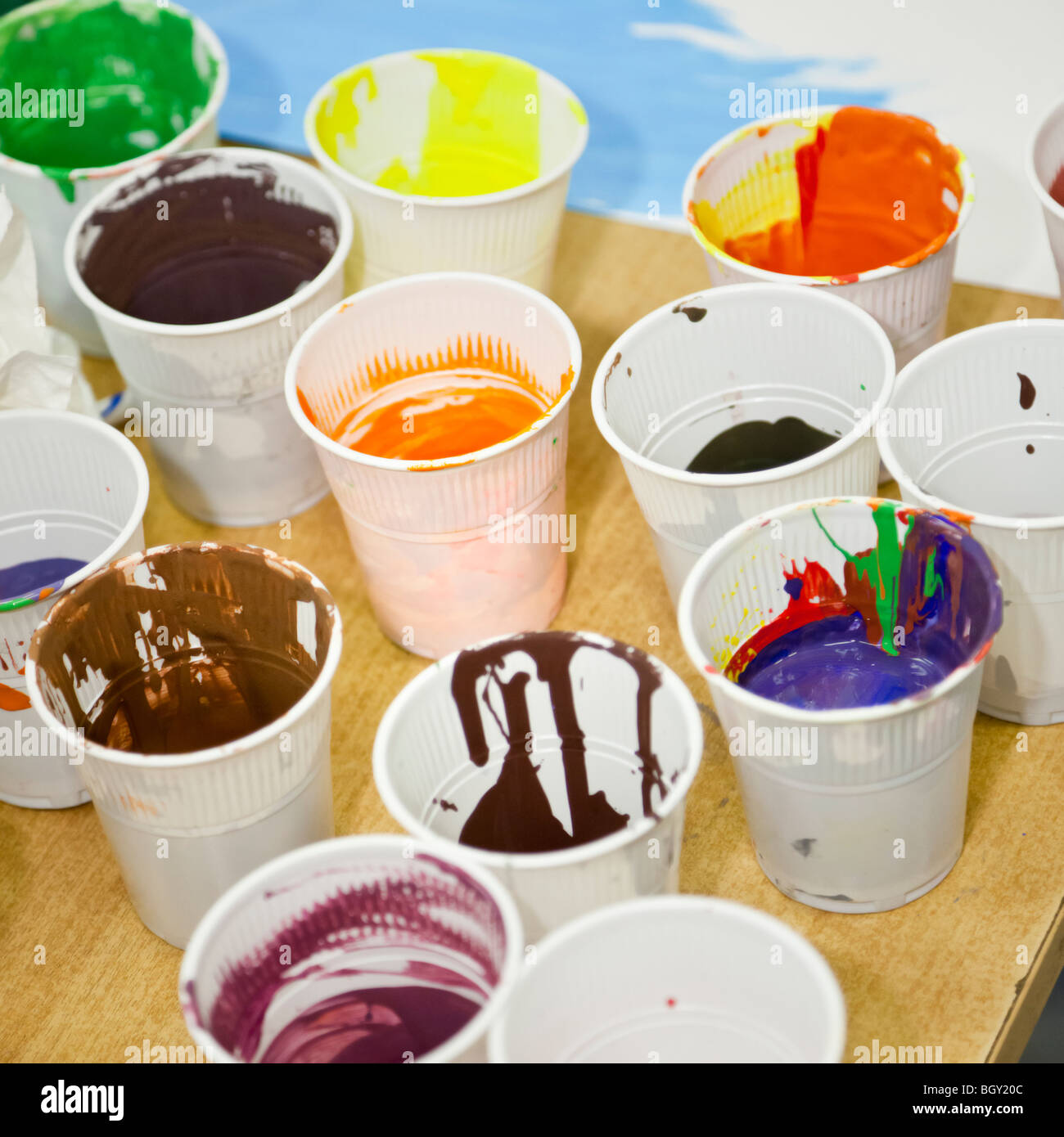 Plastic cups full of children's paint on a wooden table Stock Photo