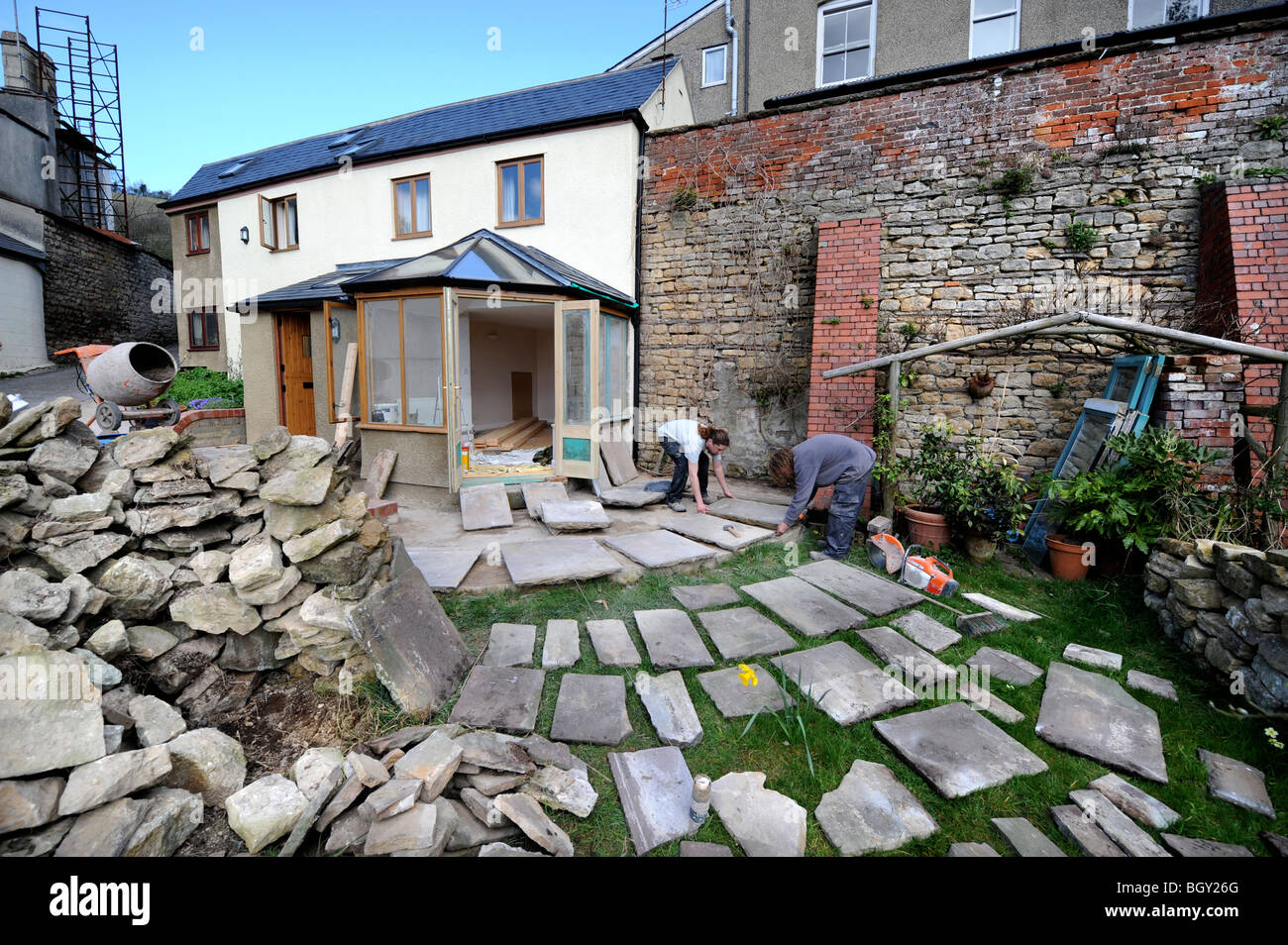 Builders lay out natural stone slabs in planning a patio, Gloucestershire UK Stock Photo