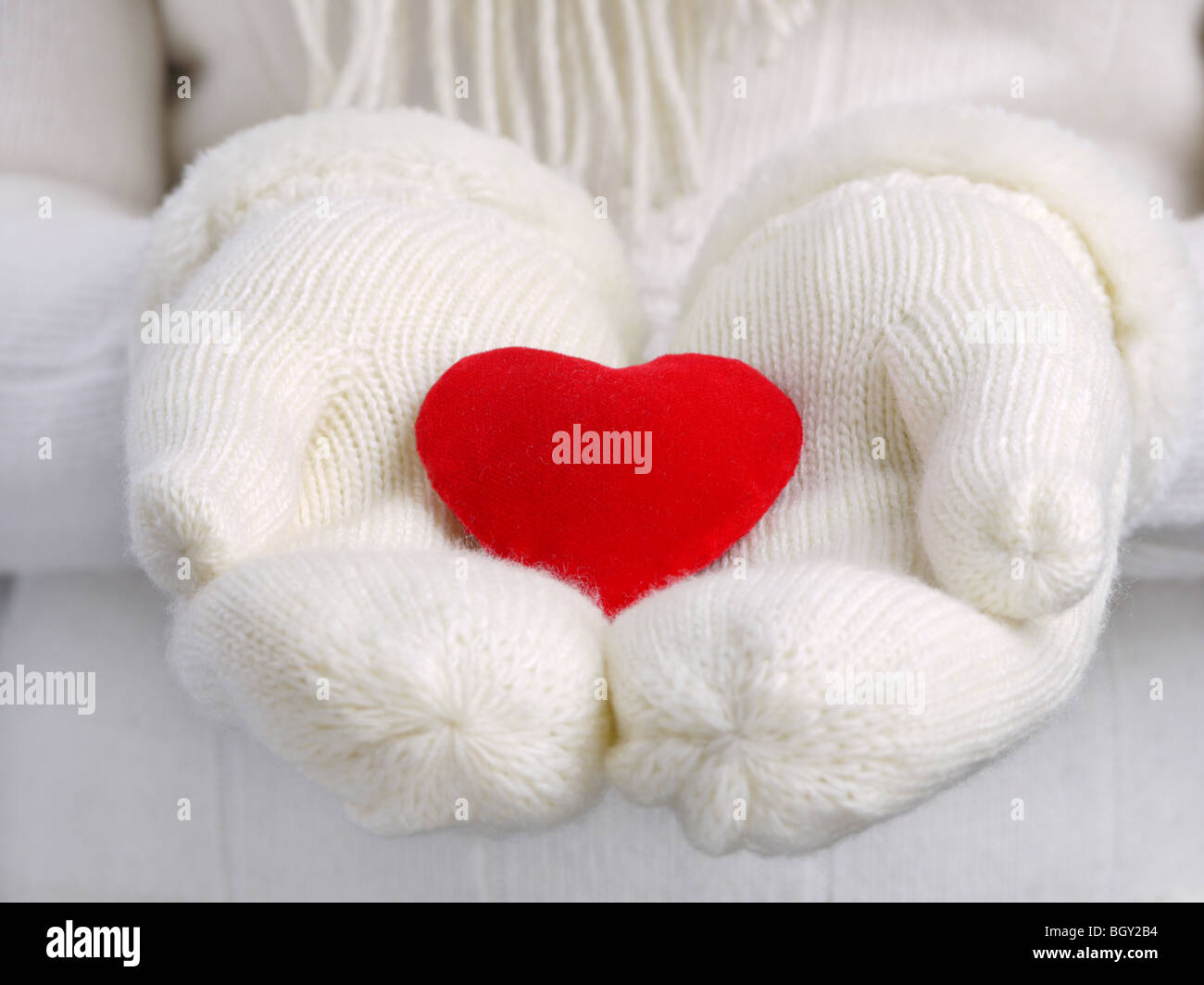 Read heart on female palms in white warm wool gloves representing Valentine's Day concept Stock Photo