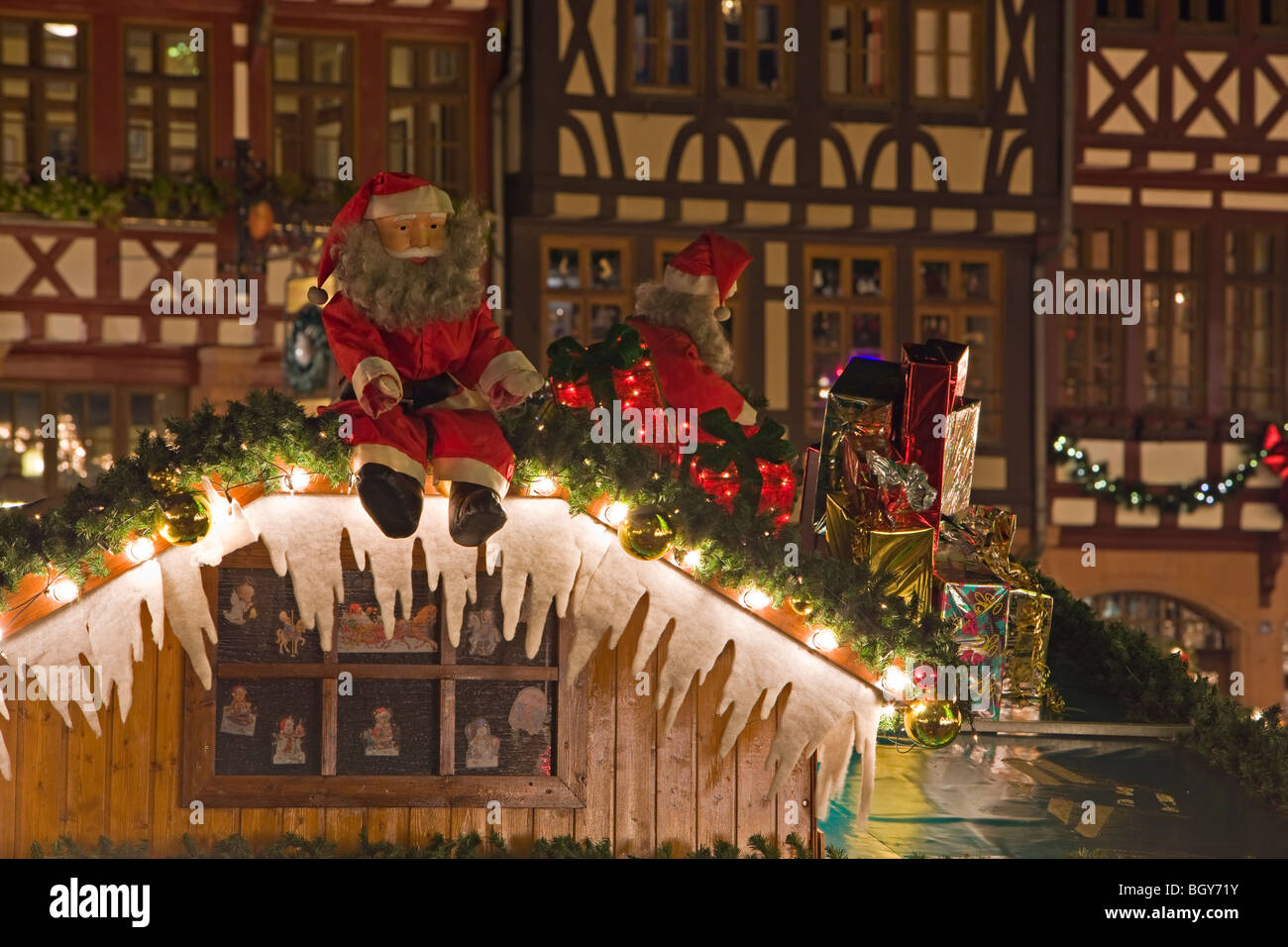 Santas Claus on the roof of a decorated Christkindlmarkt (Christmas Market) stall set up in front of buildings in the Römerberg  Stock Photo
