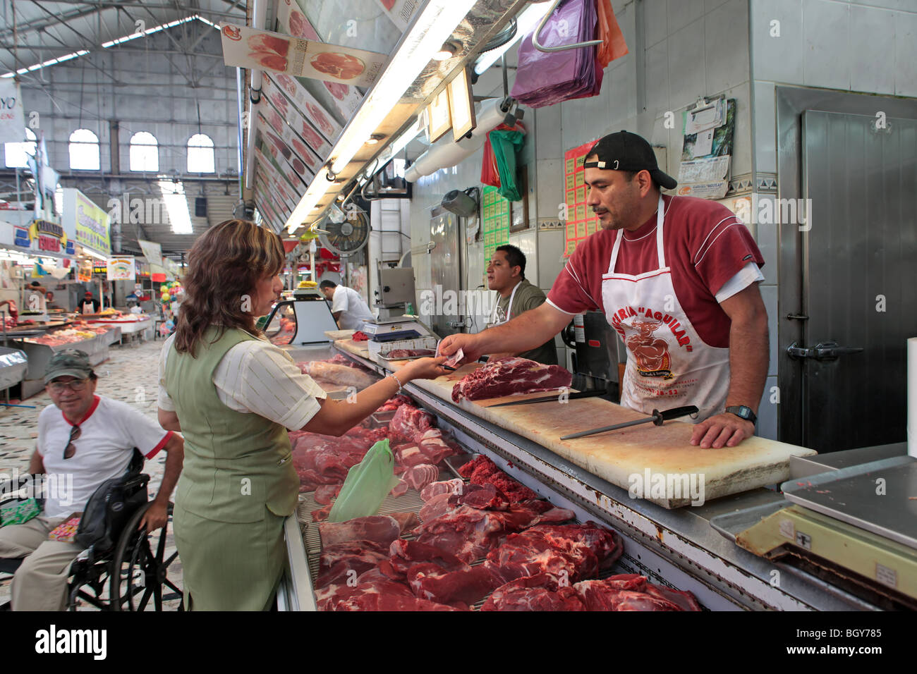 Meat market in Mazatlan Mexico, butcher selling to a customer. Covered large flea market with