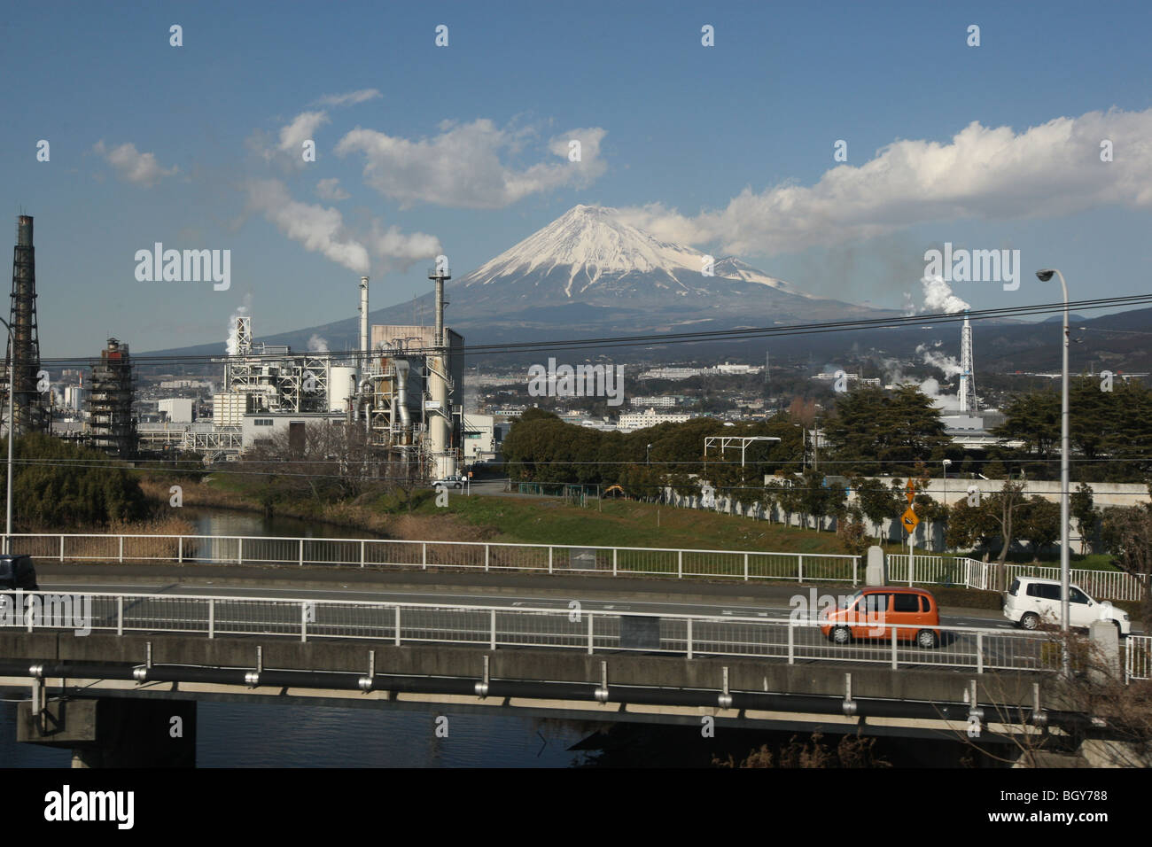Mount Fuji, seen behind a backdrop of agricultural and industrial landscape, from a shinkansen bullet train window, Japan. Stock Photo