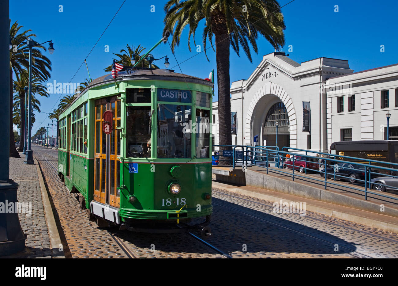 A historical CABLE CAR runs along the tracks in front of PIER 3 on THE EMBARCADERO - SAN FRANCISCO, CALIFORNIA Stock Photo