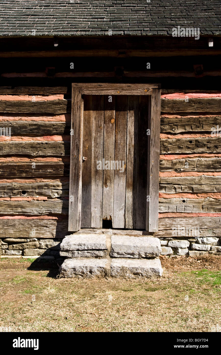 An old log building including main doorway with large stone steps. Stock Photo