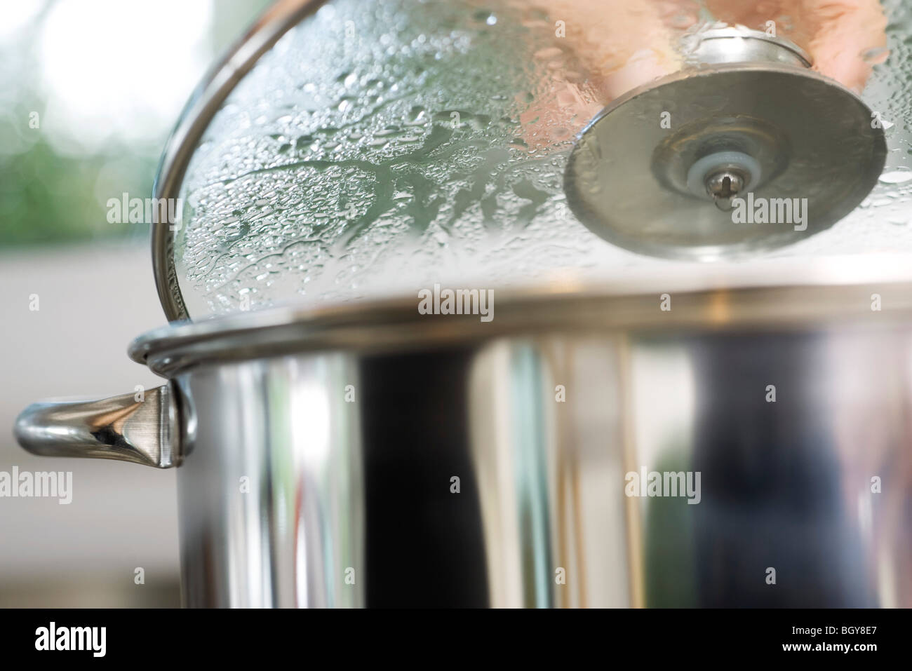 Person removing lid from steaming pot Stock Photo